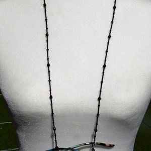 May include: A black beaded eyeglass chain with a pair of blue-framed glasses hanging from it.