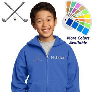 May include: A royal blue zip-up hoodie with a white embroidered design of two crossed golf clubs and a golf ball. The hoodie has a white embroidered name "Nicholas" on the front.