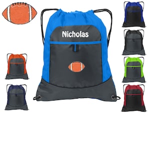 May include: A blue and gray drawstring backpack with a front pocket and a football design. The backpack is personalized with the name "Nicholas".