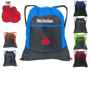 May include: Blue drawstring bag with a gray pocket and a red boxing glove design. The bag has a white name tag that says "Nicholas".