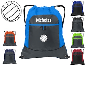 May include: A blue drawstring bag with a gray pocket and a white volleyball graphic. The bag has a white name tag that says "Nicholas". The bag is shown with other color options in the background.