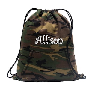 May include: Camouflage drawstring backpack with a front pocket and black drawstrings. The name "Allison" is embroidered in white script across the front. The bag features a pattern of green, brown, and tan.