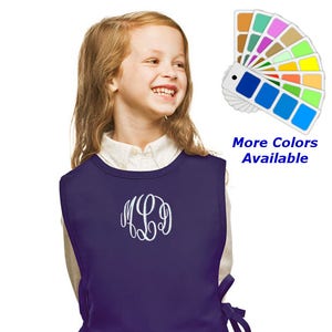May include: Purple sleeveless apron with a white monogram and a pocket. The apron has ties on the sides. More Colors Available.