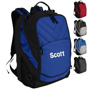 May include: A blue and black backpack with a zippered front pocket and a white embroidered name "Scott".