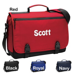 May include: A red messenger bag with a black zipper and black straps. The bag has a black mesh panel on the bottom and a white embroidered name "Scott". The bag is shown with three other color options: black, royal blue, and navy.
