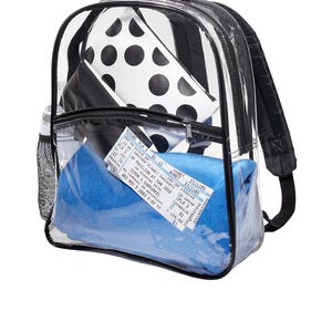 May include: A clear plastic backpack with a black zipper and black straps. The backpack is filled with a blue blanket, a black and white polka dot pouch, and a concert ticket for Simon & Garfunkel. The ticket reads "Another Planet Presents An Evening with Simon & Garfunkel, HP Pavilion at San Jose, Wed Nov 5 2003 8:00 PM."