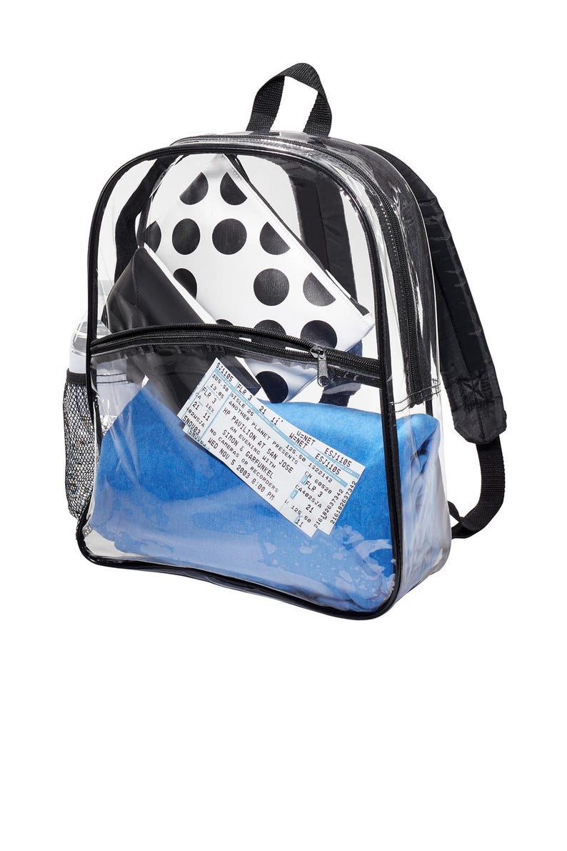 May include: A clear plastic backpack with a black zipper and black straps. The backpack is filled with a blue blanket, a black and white polka dot pouch, and a concert ticket for Simon & Garfunkel. The ticket reads "Another Planet Presents An Evening with Simon & Garfunkel, HP Pavilion at San Jose, Wed Nov 5 2003 8:00 PM."