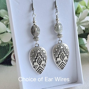 May include: Silver dangle earrings with a geometric pattern and a round bead. The earrings have a choice of ear wires.