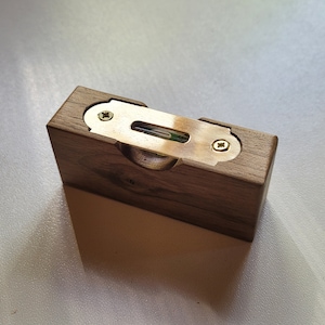May include: A small wooden box with a brass level inside. The level is set into the box and secured with screws.