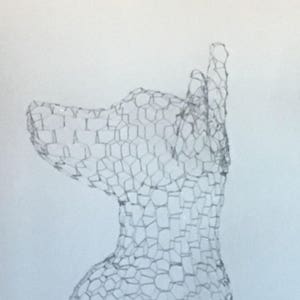 May include: A wire mesh sculpture of a dog's head, viewed from the side. The sculpture is made of a fine wire mesh, creating a delicate and intricate design.