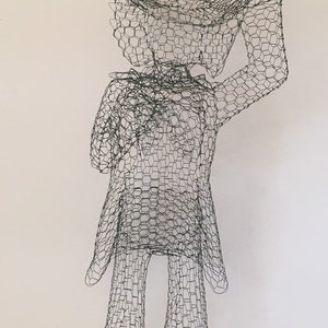 May include: A wire mesh sculpture of a person wearing a top hat and a suit. The sculpture is made of chicken wire and is a whimsical and unique piece of art.