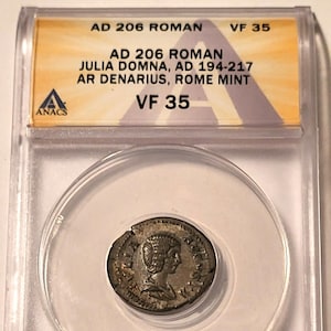 May include: A Roman coin, AD 206, featuring Julia Domna, AD 194-217, AR Denarius, Rome Mint, graded VF 35 by ANACS. The coin is encased in a clear protective holder, with visible text at the top.