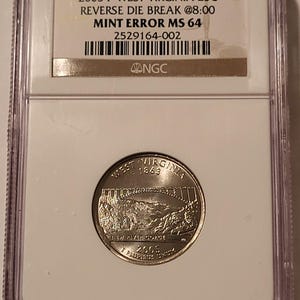 May include: A 2005 P West Virginia 25-cent coin encapsulated in a clear NGC plastic slab. The label reads 2005 P WEST VIRGINIA 25C REVERSE DIE BREAK @8:00 MINT ERROR MS 64 2529164-002. The coin features the New River Gorge bridge design.