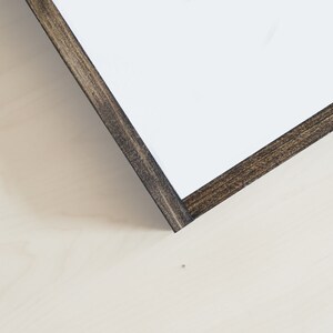 May include: Close-up of the corner of a wood frame with a dark brown stain. The frame is made of wood and has a smooth finish.