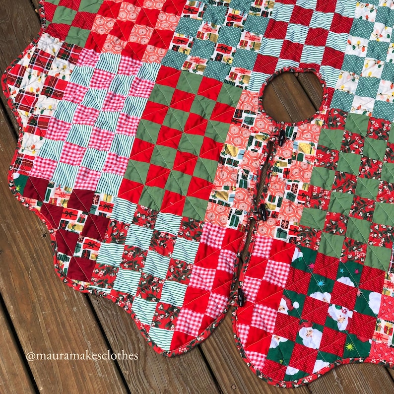 May include: A handmade Christmas tree skirt with a patchwork design. The skirt features red, green, and white fabrics with various patterns, including checks, stripes, and gift box motifs. The skirt has a scalloped edge and a center opening.
