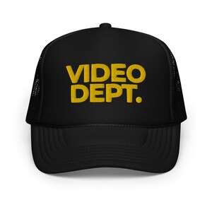 May include: Black trucker hat with a yellow embroidered logo that says "VIDEO DEPT."