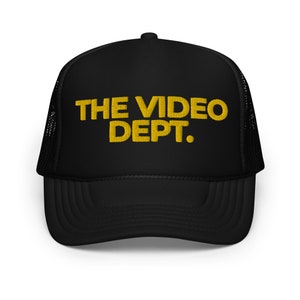 May include: Black trucker hat with a yellow embroidered logo that says "THE VIDEO DEPT."