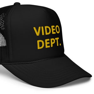 May include: Black trucker hat with a yellow embroidered design that says "VIDEO DEPT."