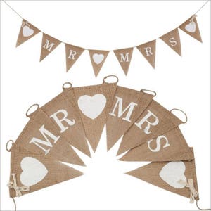 May include: A burlap banner with white hearts and the words "MR" and "MRS" printed on it. The banner is strung together with twine and is perfect for a wedding or engagement party.