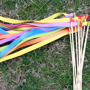 May include: A set of rainbow ribbon wands with wooden sticks. The ribbons are in the colors of the rainbow: red, orange, yellow, green, blue, indigo, and violet. The sticks are natural wood.