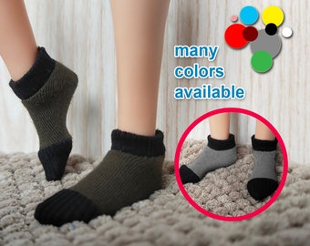 May include: A pair of ankle socks in a dark green and black color combination. The socks are made of a soft, ribbed fabric. The image shows the socks on a person's feet, with the text "many colors available" displayed above the socks.