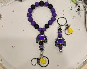 Llavero de silicona con cuentas y dije de pato, con forma de camión todoterreno, color morado.
