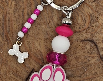 Llavero con cuentas y huella de pata rosa con dije de hueso de perro, ideal para amantes de los perros.
