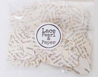 May include: A clear plastic bag filled with small white paper hearts, each with text printed on them. The bag has a round label that says "Lace Pearl & Paper".