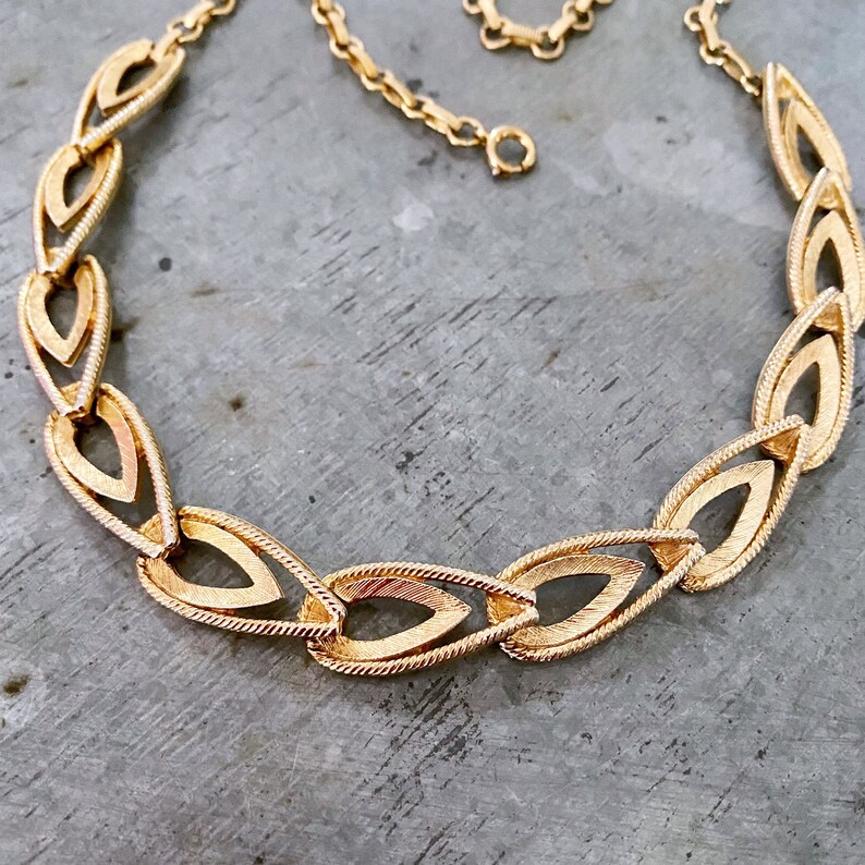 May include: A gold-tone necklace with a chain link design featuring interlocking teardrop-shaped links.