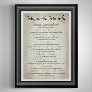 May include: Framed print featuring the text "Miyamoto Musashi Samurai Commandments" in a black frame. The print has a parchment-like background with black text. The commandments are numbered and listed in a classic font.