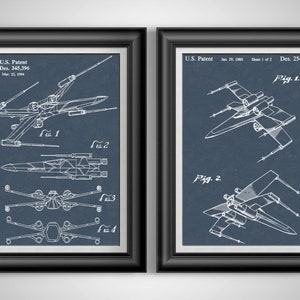 May include: Two framed prints featuring white technical drawings of a spacecraft on a dark blue background. The left print shows multiple views, with the text "U.S. Patent Des. 345,396 Mar. 12, 1994." The right print shows two views with the text "U.S. Patent Jan. 29, 1980 Sheet 1 of 2 Des. 254,080."