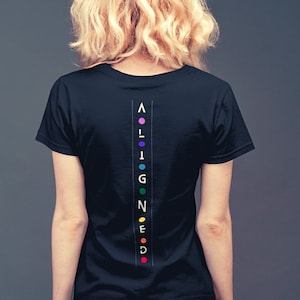 Könnte beinhalten: Ein schwarzes T-Shirt mit dem Wort "ALIGNED" vertikal auf dem Rücken geschrieben. Jeder Buchstabe hat eine andere Farbe des Regenbogens.