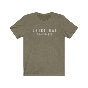 May include: Olive green t-shirt with the words "SPIRITUAL savage" printed in white. The top text is in a sans-serif font, and the bottom word is in a cursive font. The shirt has short sleeves and a crew neck.
