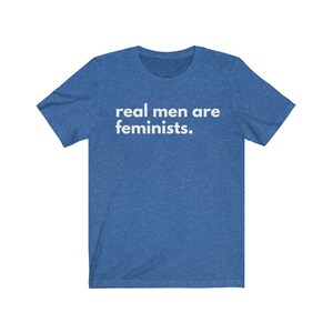 May include: A blue t-shirt with the text "real men are feminists." printed in white.