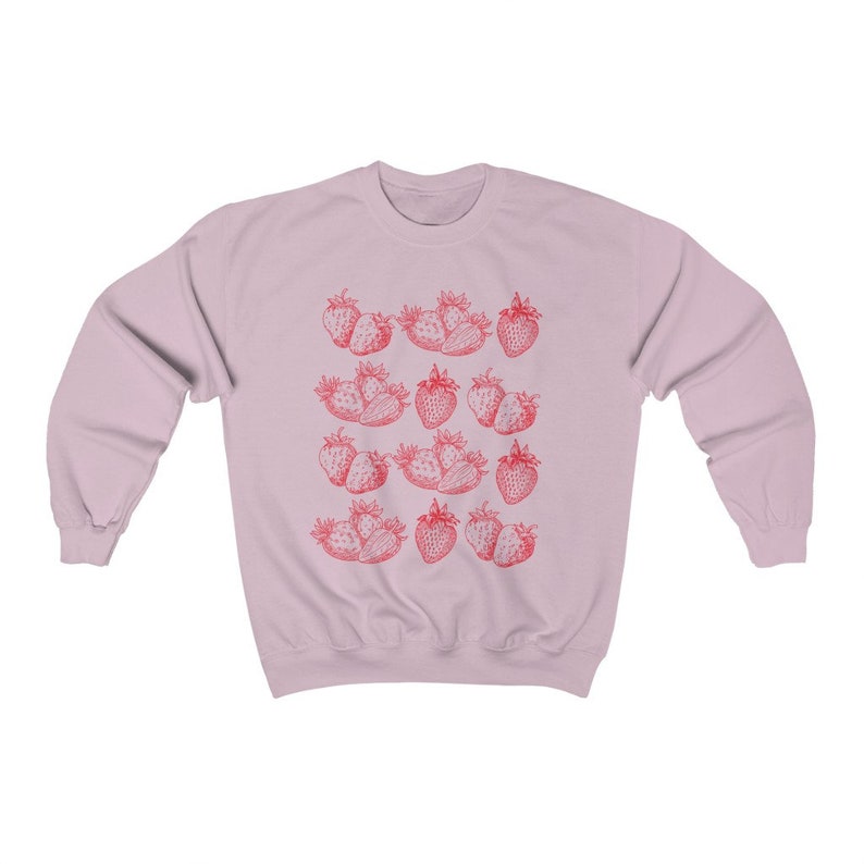 May include: A pink sweatshirt with a repeating pattern of red strawberries. The strawberries are drawn in a vintage style.