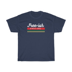 May include: Navy blue t-shirt with the text "Free-ish Since 1865" in white script. The text is above a horizontal stripe design in red, green, yellow, and black. The shirt is a casual wear item.
