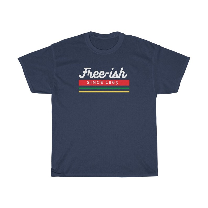 May include: Navy blue t-shirt with the text "Free-ish Since 1865" in white script. The text is above a horizontal stripe design in red, green, yellow, and black. The shirt is a casual wear item.