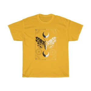 K&ouml;nnte beinhalten: Ein gelbes T-Shirt mit einer schwarzen und wei&szlig;en Mottenillustration in der Mitte. Die Motte ist von einem geometrischen Design mit Halbmonden und anderen Symbolen umgeben.