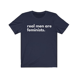 May include: Navy blue t-shirt with white text that reads "real men are feminists."