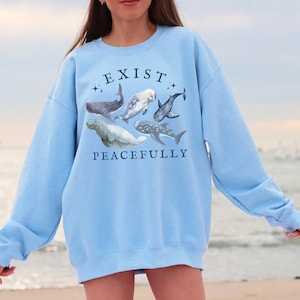 May include: Light blue sweatshirt with a graphic of various sea creatures and the text "EXIST PEACEFULLY" printed on the front.
