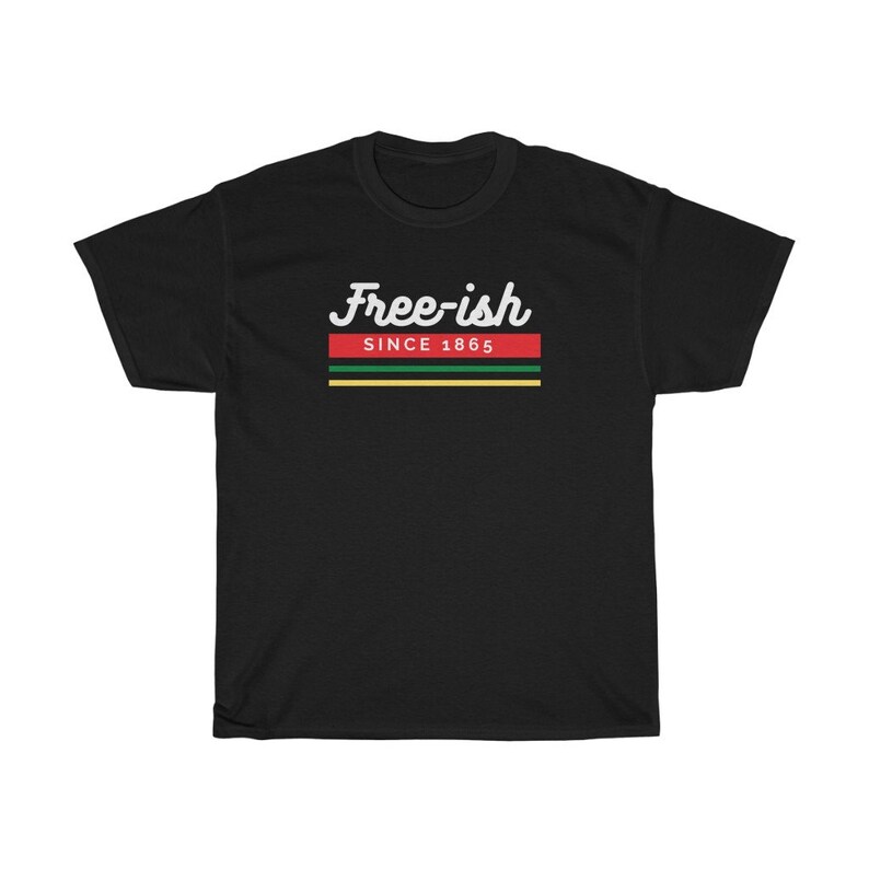 May include: Black t-shirt with the text "Free-ish Since 1865" in white script above a horizontal stripe design in red, green, and yellow. The shirt is a casual wear item.