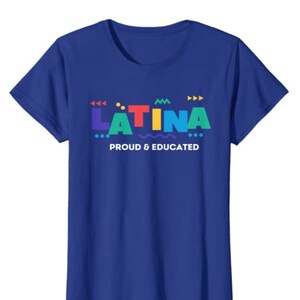 May include: A royal blue t-shirt with the word "LATINA" in colorful, geometric letters. Below the word is the phrase "PROUD & EDUCATED" in white. The shirt is a classic crew neck style.