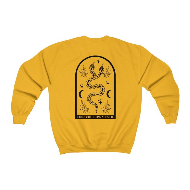 May include: Mustard yellow sweatshirt with a black graphic on the back. The graphic features two snakes intertwined within an arched frame, with crescent moons, stars, and the text "FIND YOUR OWN PATH".