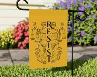 Könnte beinhalten: Eine gelbe Gartenflagge mit einer schwarzen Illustration von zwei blind gebundenen Figuren, die eine Waage halten. Der Text "RESIST" ist vertikal zentriert auf der Flagge.