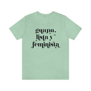 May include: A light green t-shirt with the words "guapa, lista y feminista" in black script. The shirt is a solid color and has short sleeves.