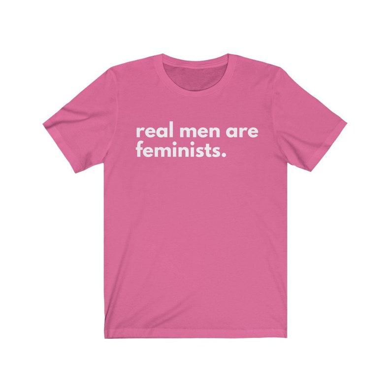 May include: Pink short-sleeved t-shirt with the text "real men are feminists." printed in white.