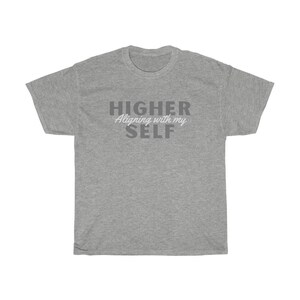 May include: Gray t-shirt with the text "HIGHER Aligning with my SELF" in gray and white lettering.