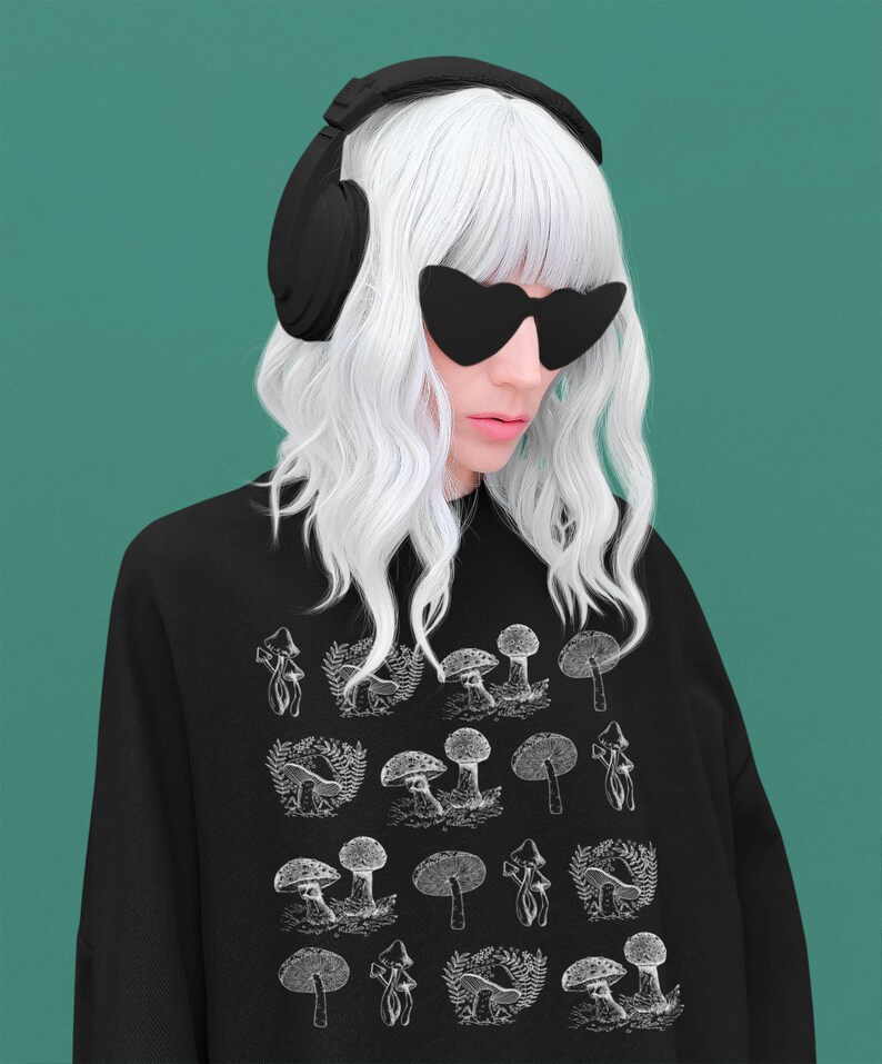 May include: A black sweatshirt with a white graphic print of mushrooms. The model is wearing black headphones and sunglasses.