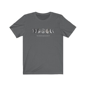 May include: A dark gray t-shirt with a graphic of the moon phases and the text "THE MOON MADE ME DO IT".
