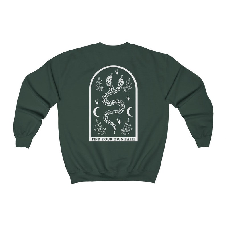 May include: Dark green sweatshirt with a white graphic of two intertwined snakes, crescent moons, stars, and leaves inside an arched frame. The text "FIND YOUR OWN PATH" is below the frame.